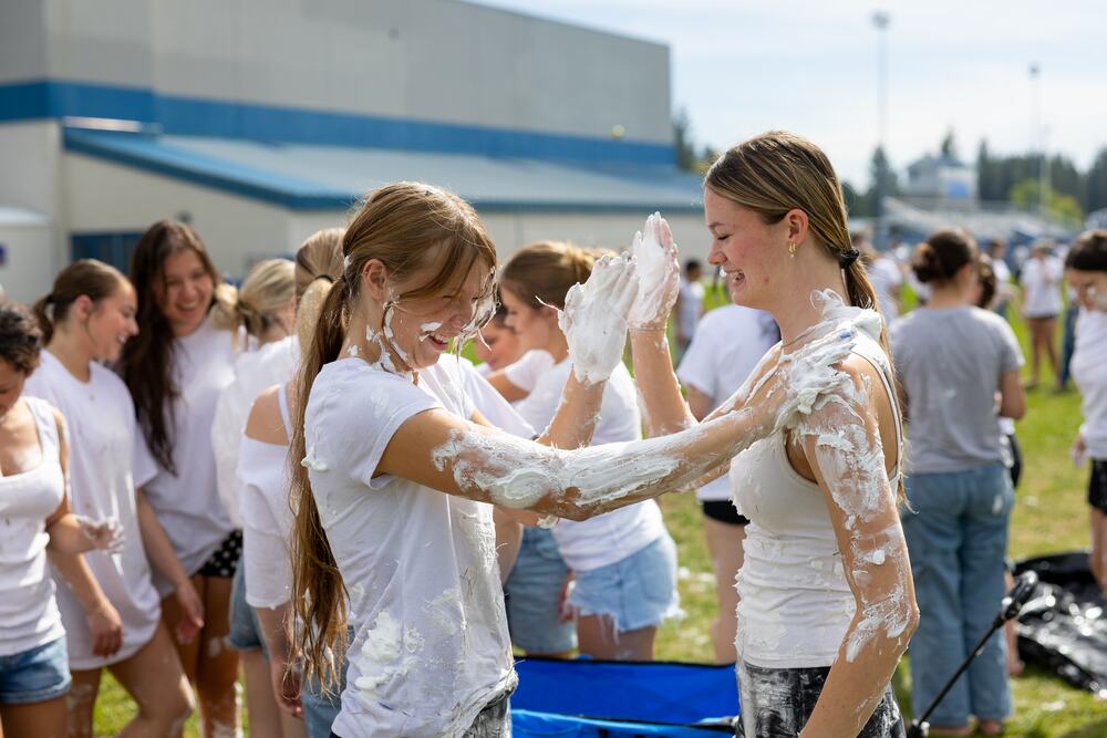 Seniors in the middle of the shaving cream fight, arms full of it, reaching for each other.