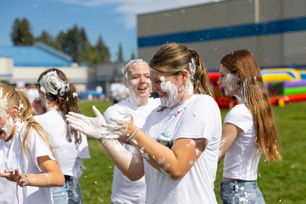 Three seniors laughing with shaving cream smeared through their hair and down their shirts.