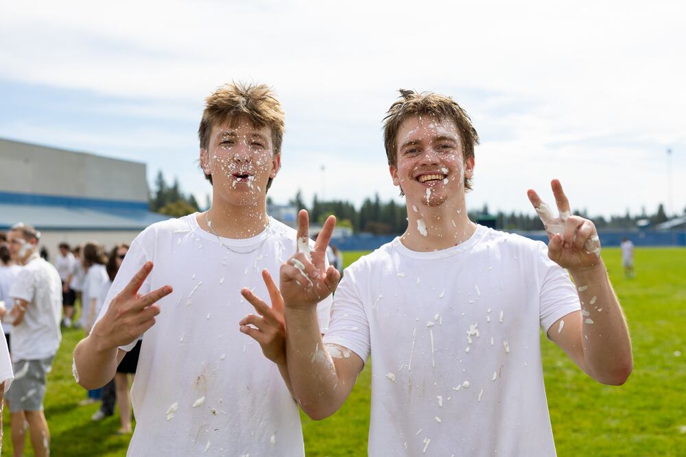Two seniors covered in shaving cream throwing peace signs at the camera.