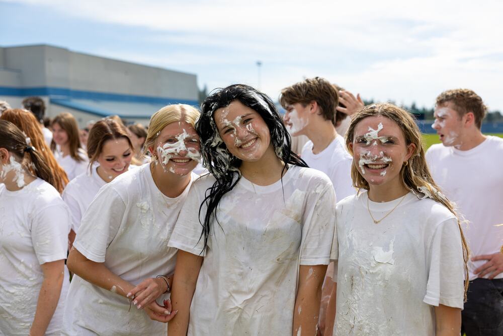 Four seniors laughing together with shaving cream on their faces and in their hair.