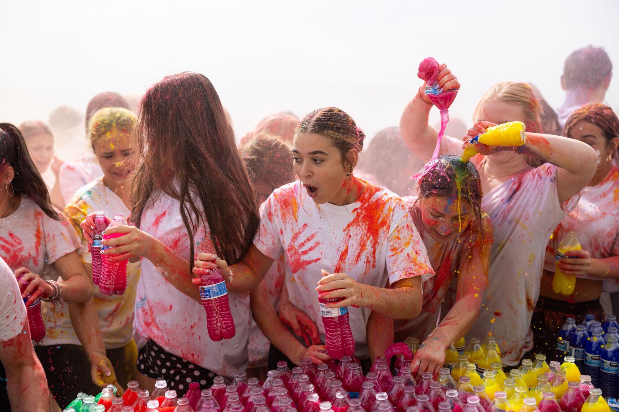 CHS seniors holding bottles of colored water at Senior Start, one of them pouring pink over a classmate's head
