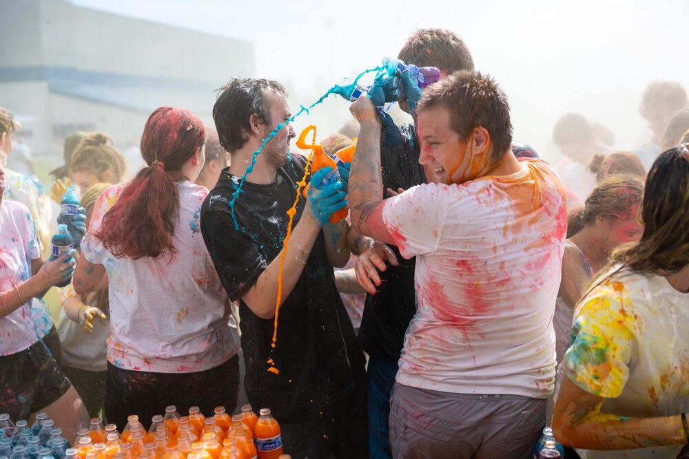 A senior pouring a bottle of blue color over a classmate at close range.