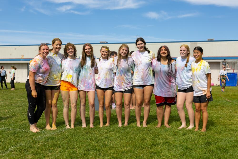 A row of senior girls covered in color standing together on the field.
