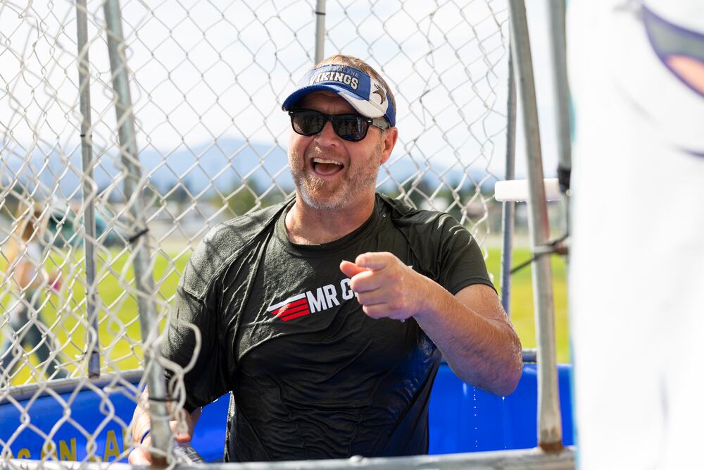 A volunteer laughing from inside the dunk tank cage, soaked through.