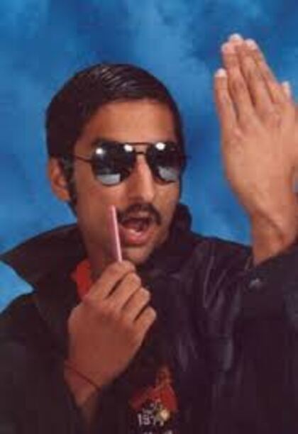 A senior in sunglasses holding a hand up beside his face