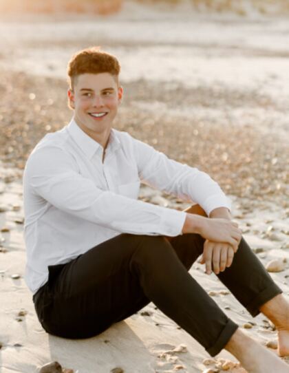 A senior sitting full length on a beach walkway